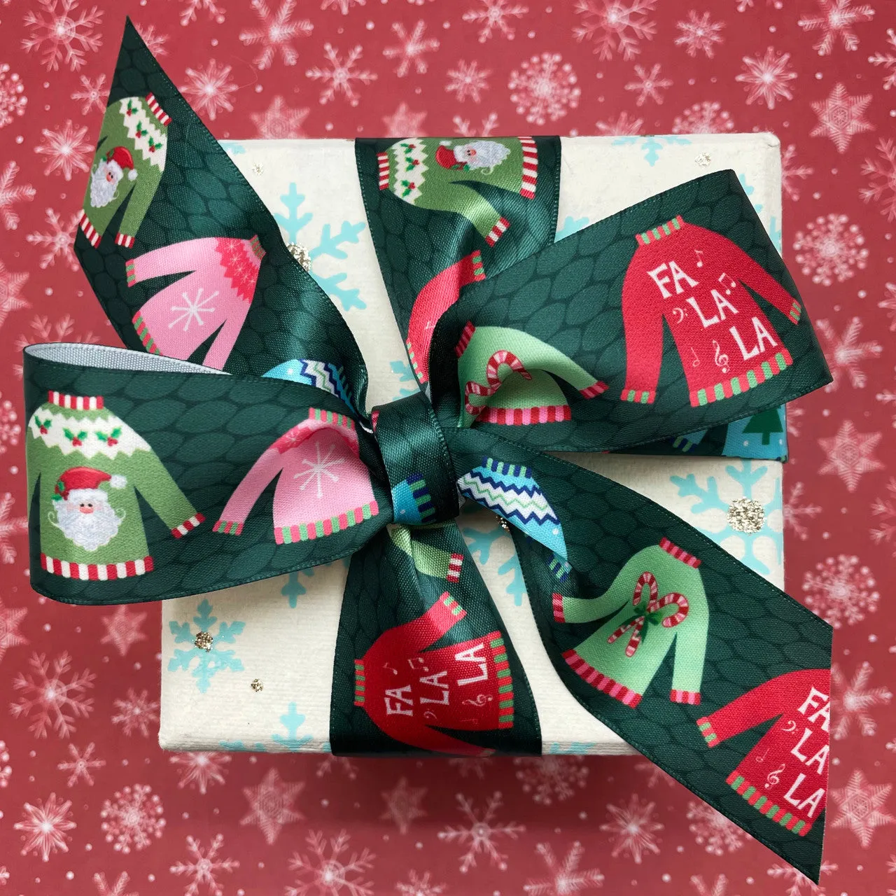 Christmas Ribbon Sweaters in primary colors on a green knit background printed on 1.5" white satin